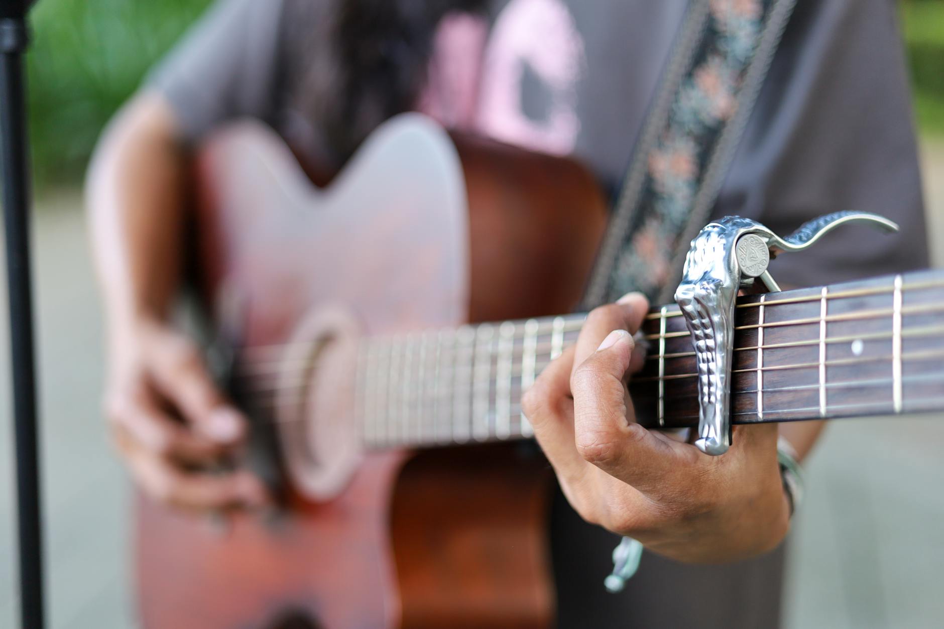 guitarist playing acoustic guitar with capo on the fretboard